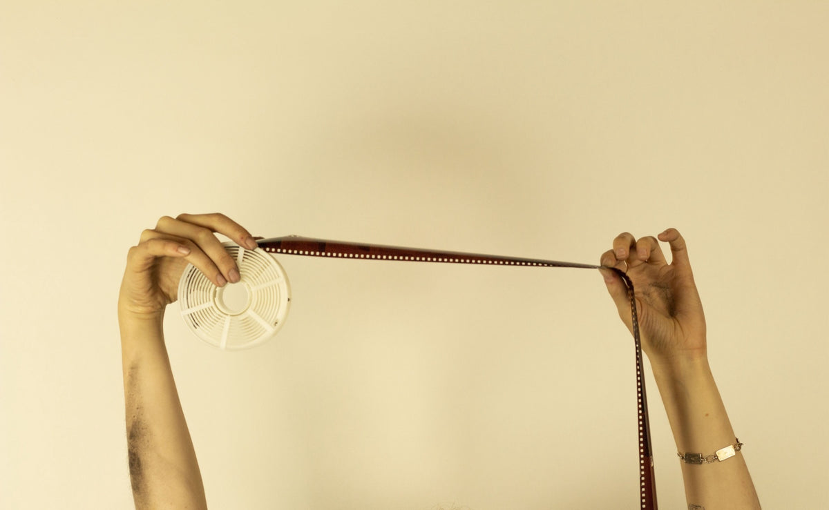 Hands winding a roll of film onto a developing reel