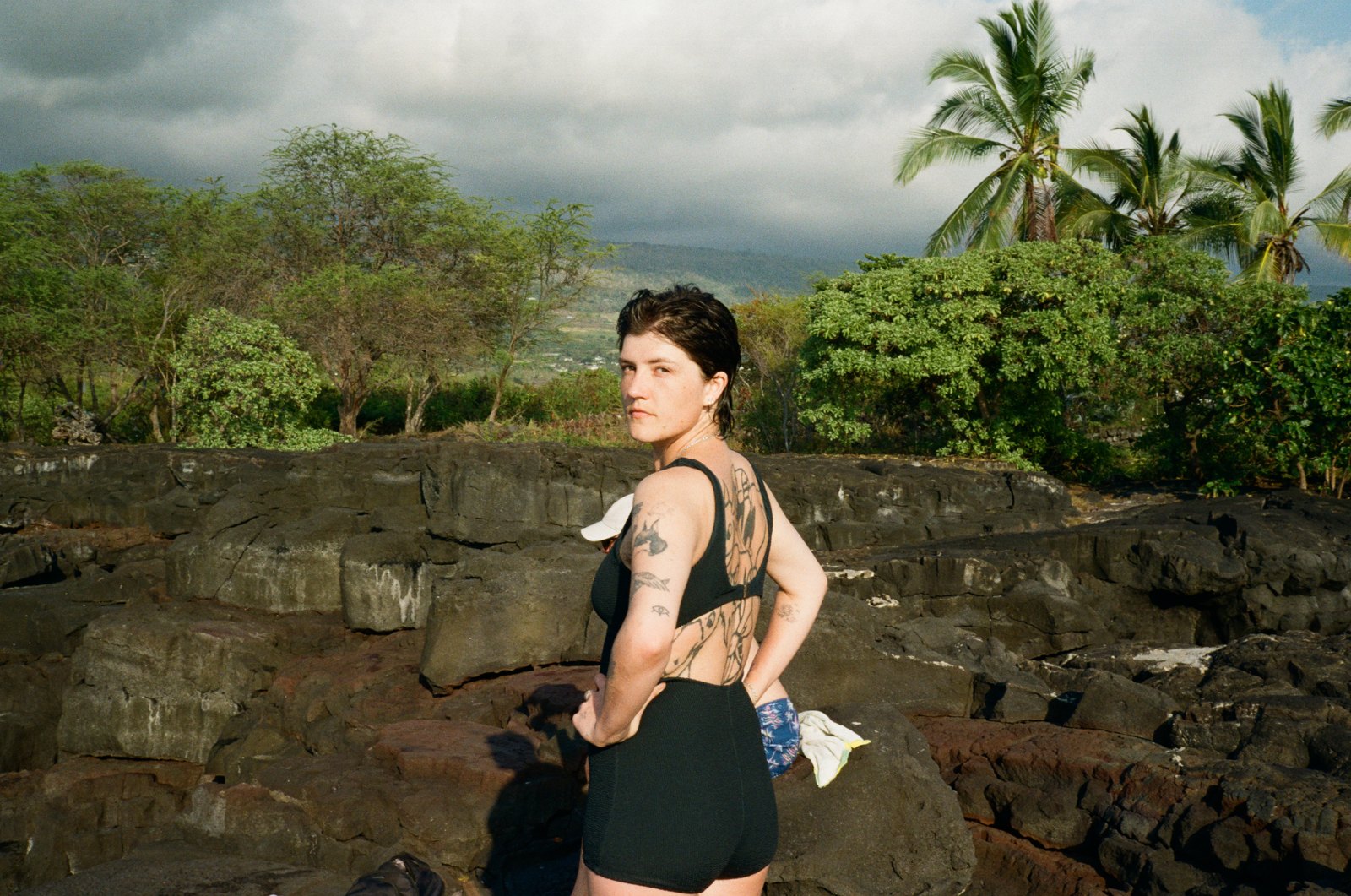 Woman standing on volcanic rock by the sea, shot on 35mm